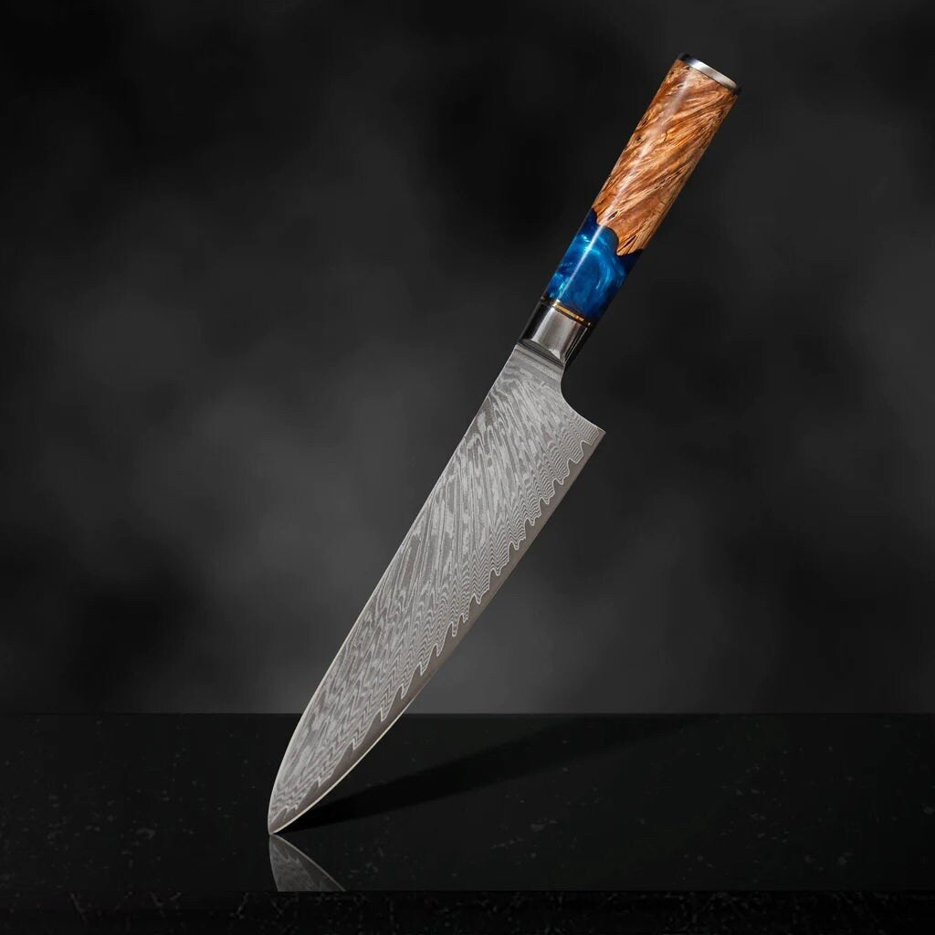 8 inch engraved Damascus chef knife with blue resin and pakka wood handle on dark wood surface with fresh fish and herbs